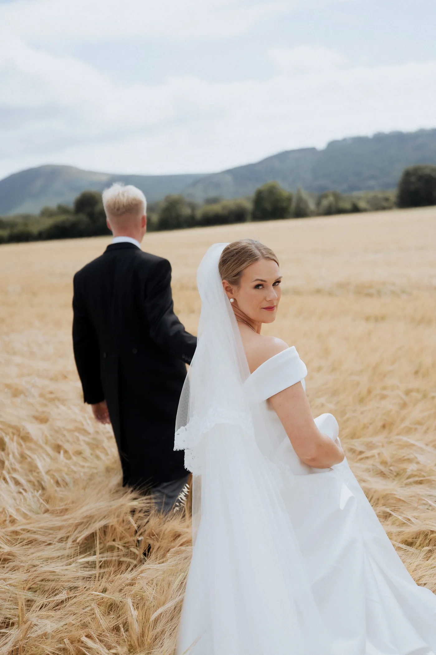 Natalie looking back across a sunlit field beside Spencer