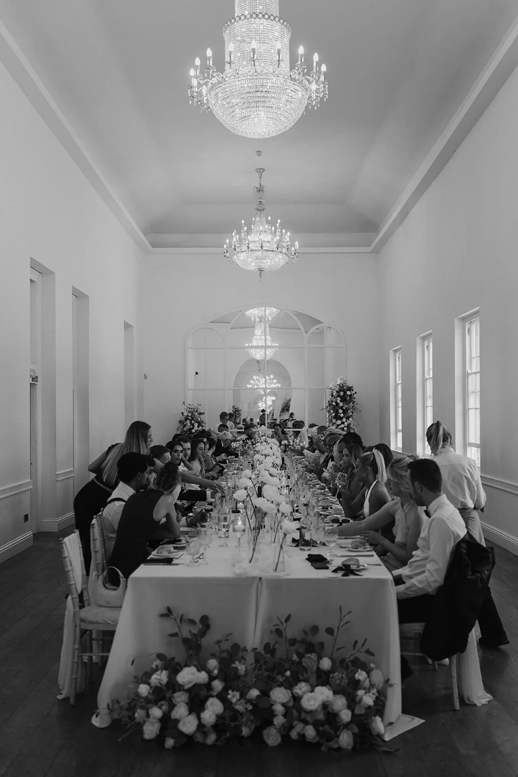 Black-and-white photograph of a long floral wedding reception table
