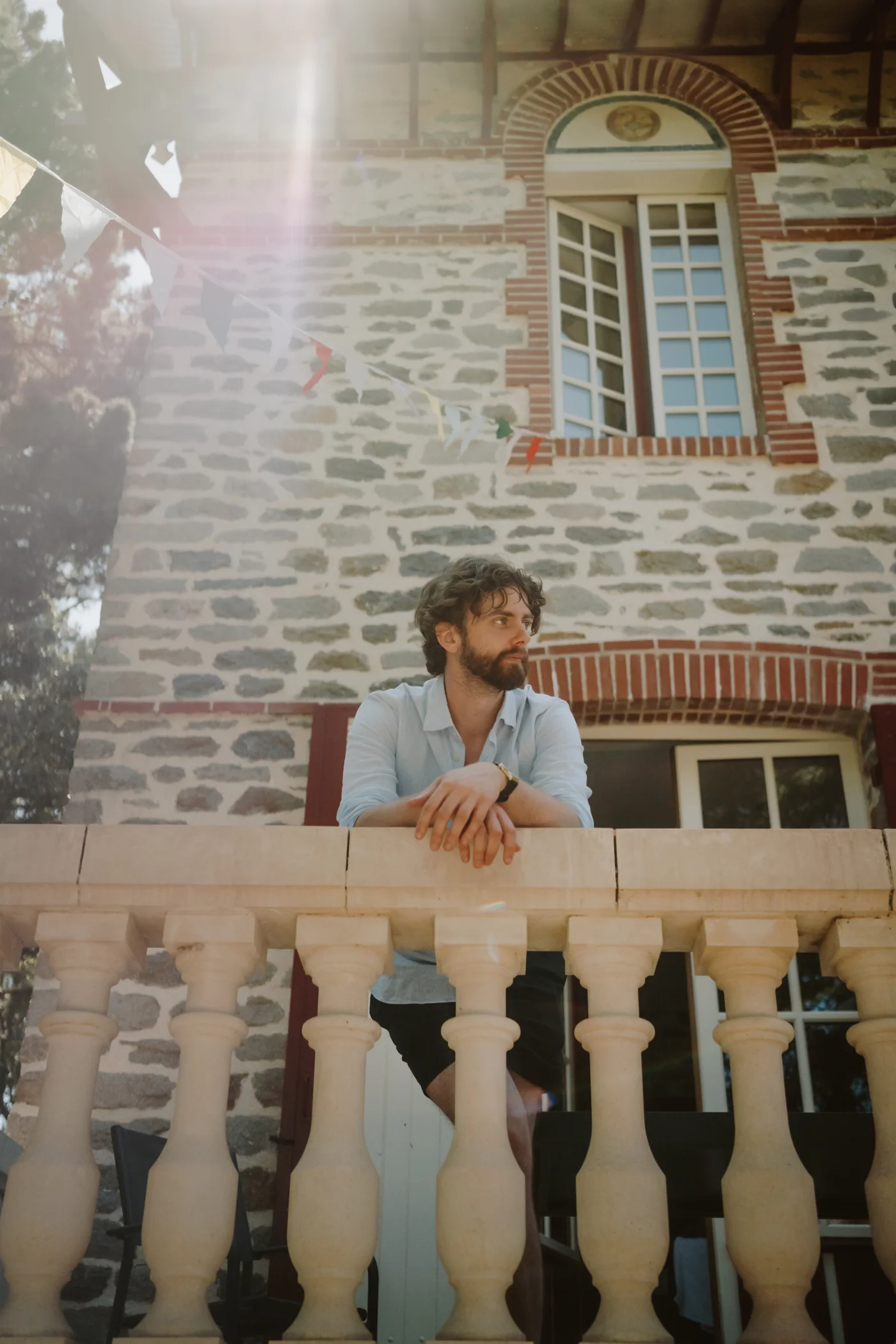 Tom Wyatt leaning on a stone balcony in the sunshine